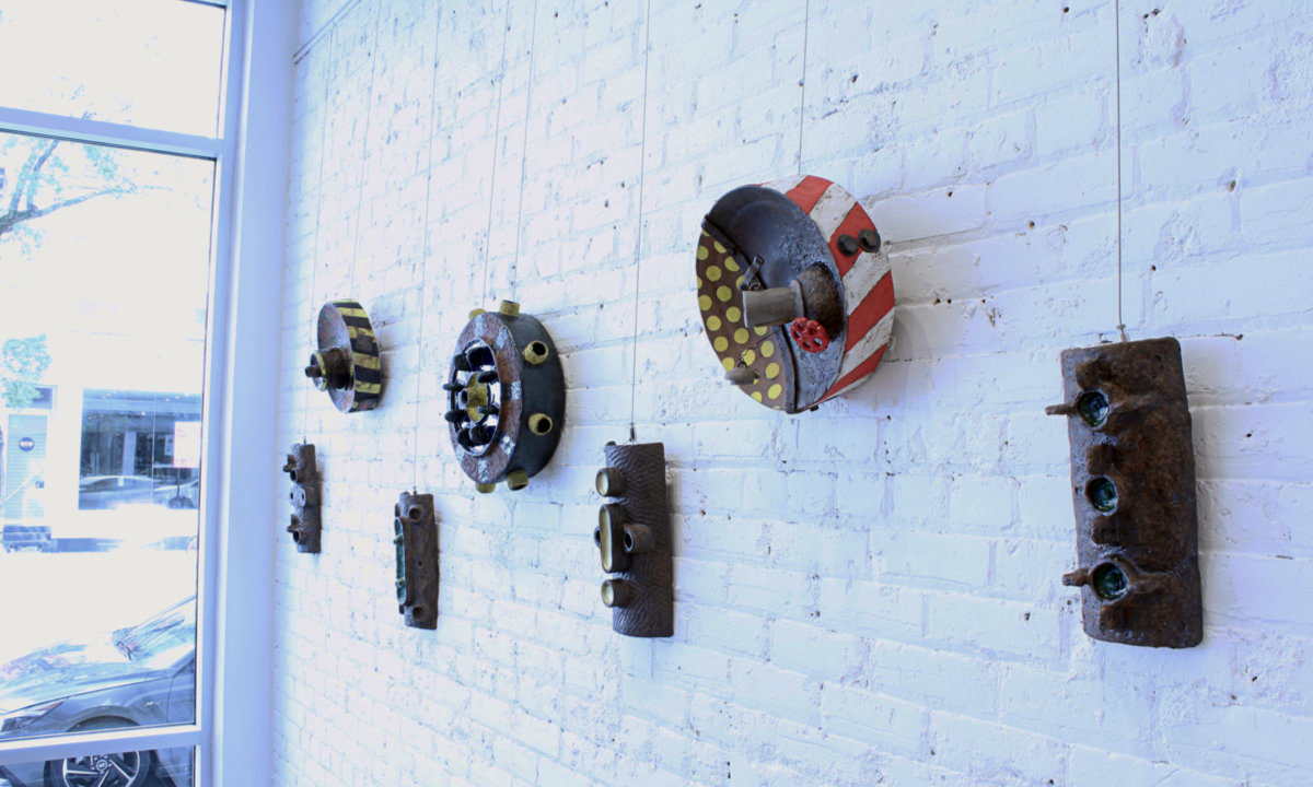Display of Metallics art works hung on a white painted brick wall at Galerie Erga.